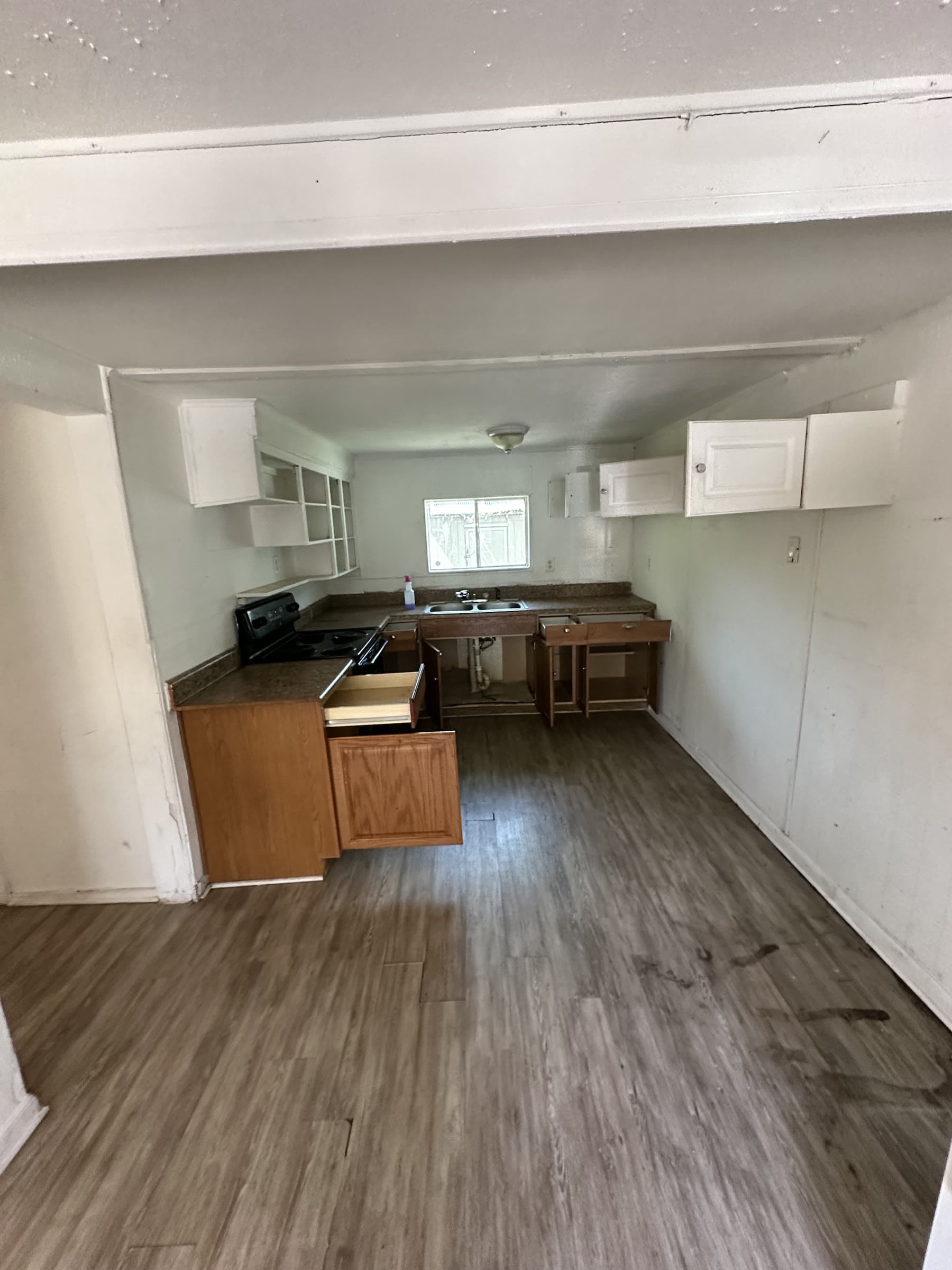 Kitchen with missing lower cabinet doors and exposed sink plumbing in Tampa, Florida