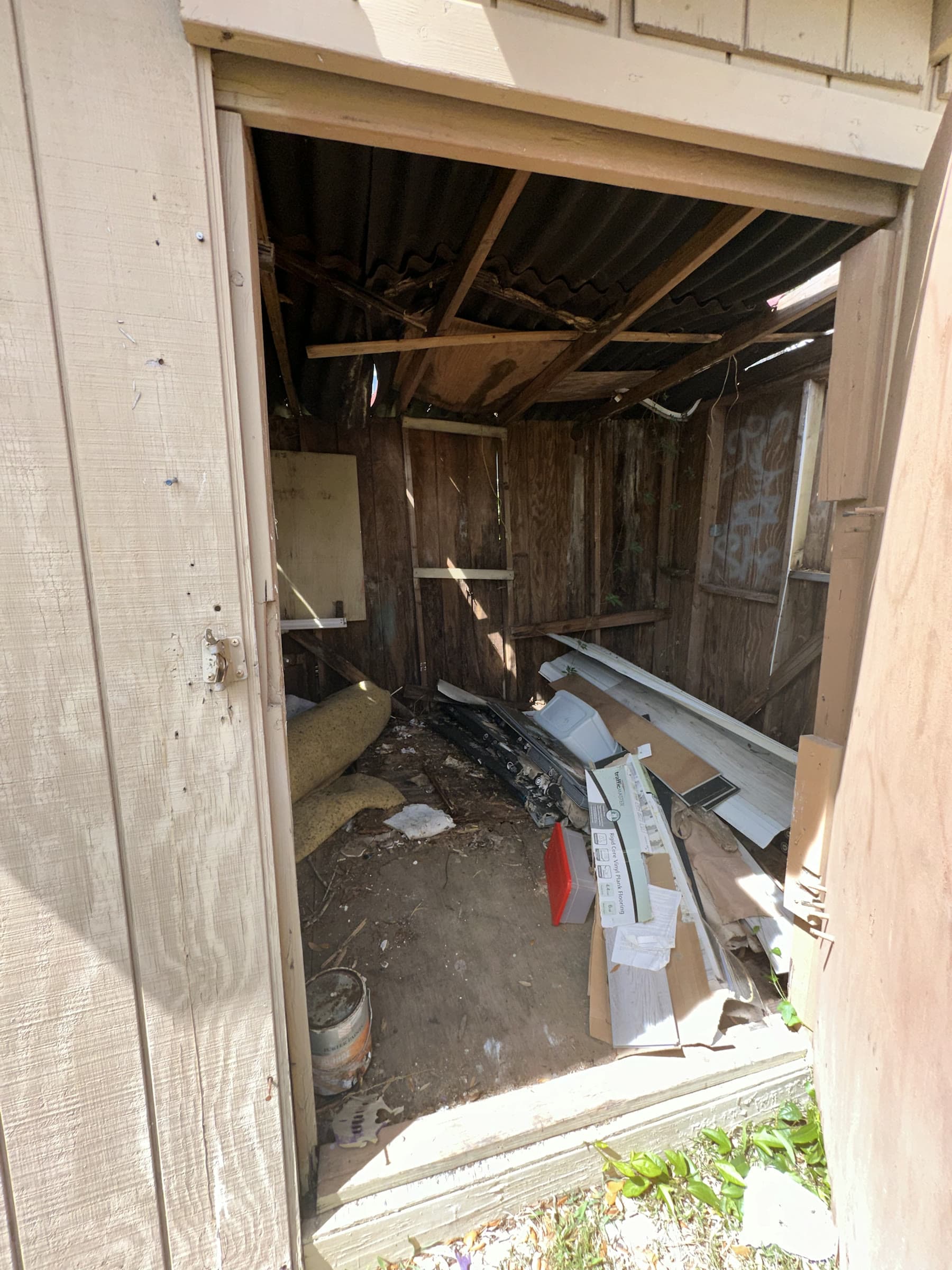 Wooden accessory structure with damaged roof panels and cleanup debris in Tampa, Florida