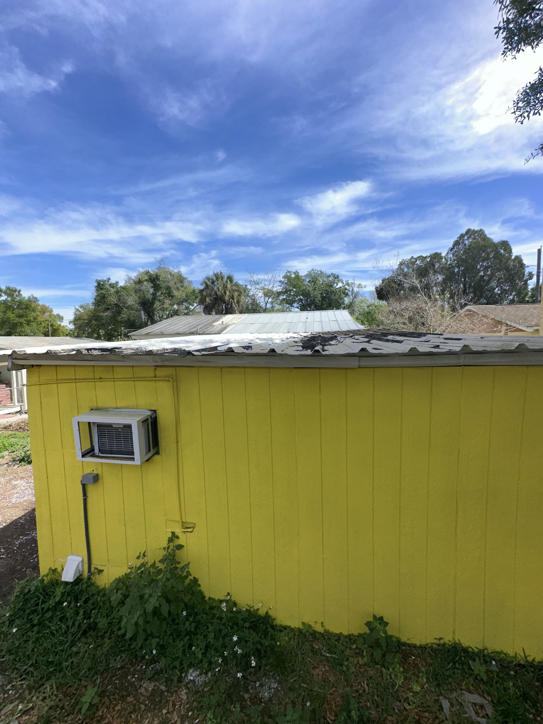 Yellow house exterior with visible wear and peeling material along the roof edge in Tampa, Florida